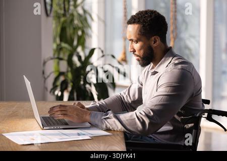 Focused African American manager man in wheelchair working at computer Stock Photo