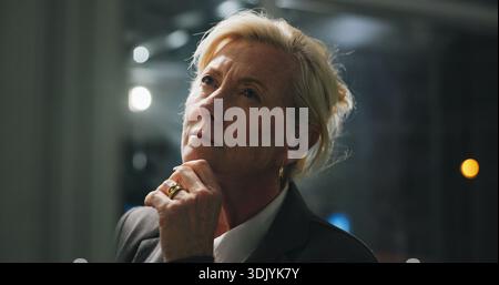 Night, thinking and mature woman in office with project, business plan and brainstorming at digital agency. Research, overtime and manager with Stock Photo