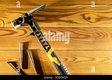 A multipurpose Claw Hammer and a variety of Nails placed on a Wooden Surface for various projects and tasks Stock Photo