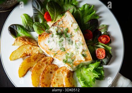 Delicious grilled swordfish steak with roasted potatoes and fresh salad. Gourmet seafood meal on a white plate. Healthy Mediterranean dinner. Stock Photo
