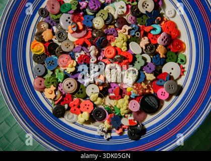 Different shapes of sewing buttons on a plate. Colorful sewing buttons texture. Stock Photo