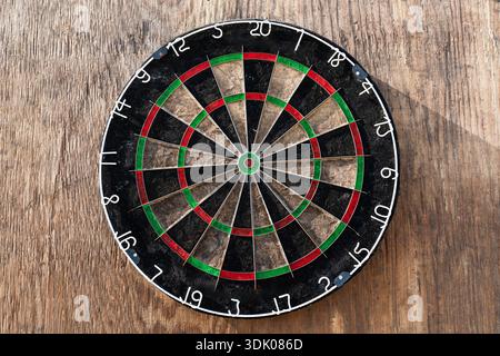 Close up of a professional dartboard hanging on a rustic wooden wall background Stock Photo