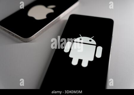 Smartphones displaying Apple and Android logos on black screens with focused view on Android operation system. High quality photo Stock Photo