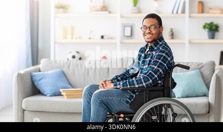 Young Man With Glasses Using a Wheelchair Sits Comfortably in a Modern Living Room Stock Photo