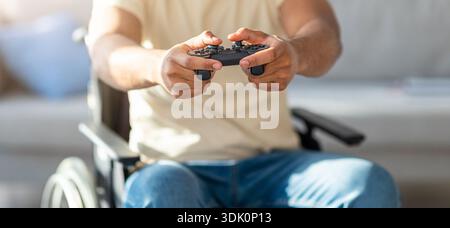 Man Using a Wheelchair Enjoys Video Games While Sitting at Home in the Afternoon Stock Photo