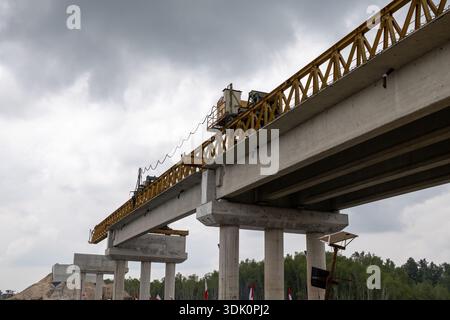 Concrete bridge under construction with precast beams installed by launching gantry, showing modern infrastructure engineering against overcast sky. Stock Photo