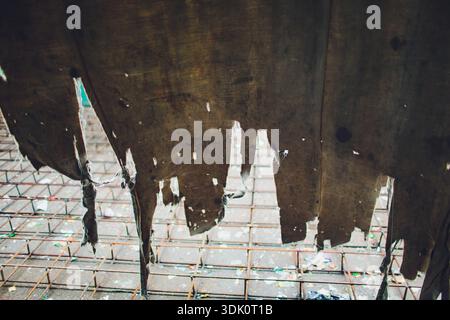 Abandoned decay visible. Rusty iron bars and worn canvas. Dusty concrete with peeling fabric fragments. Old structure showing corrosion and weathered Stock Photo
