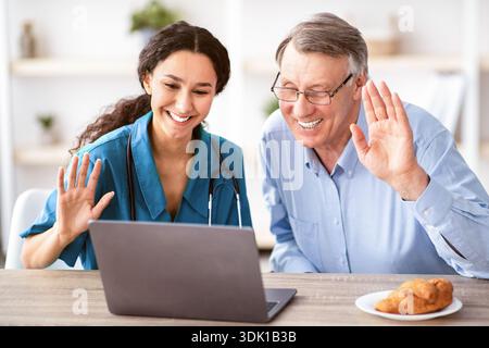 Smiling Woman With Dark Skin Using a Laptop to Connect With an Older Man in a Light Room Stock Photo