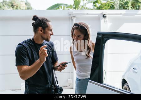 Couple having serious discussion standing next to car Stock Photo