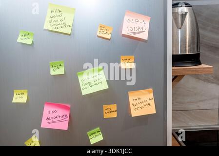 Many colored stickers glued on door refrigerator with schedule of affairs for day, details of interior kitchen Stock Photo