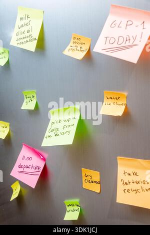 Many colored stickers glued on door refrigerator with schedule of affairs for day, details of interior kitchen Stock Photo