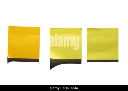 Three yellow sticky notes are arranged side by side against a white surface. The left note is a darker shade, while the two on the right are lighter. Stock Photo