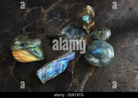 Collection of labradorite gemstones displayed in polished, raw, slab, and tower forms on a dark marble background Stock Photo