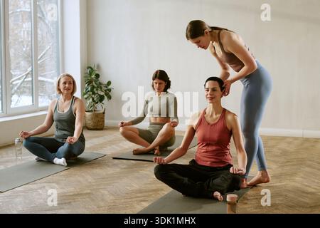 Group of Young Adult Women Practicing Yoga and Meditating Indoors Stock Photo
