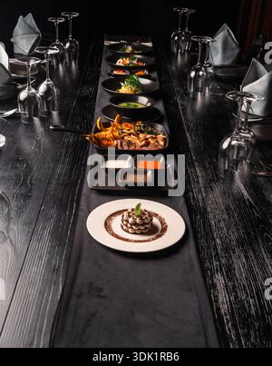 Long Dining Table Set with a Sequence of Plated Gourmet Dishes Stock Photo