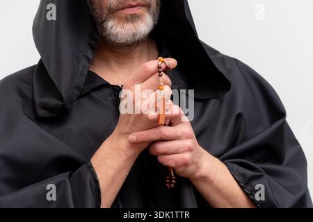 Close up of monk hands holding rosary and cross on white background Stock Photo