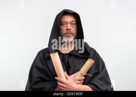 Monk in black robe holding scrolls on chest, isolated Stock Photo