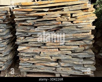 Stacked stone slabs in sunlight creating textured natural background with earthy tones. Mobile photo Stock Photo