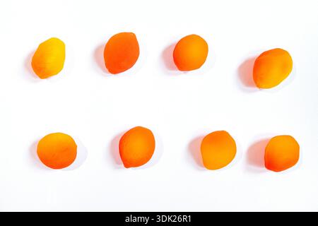Chinese Preserved Fruit Fresh red yellow Sweet Peach are arranged in a row on a white background, highlighting their vibrant colors and smooth surfaces for creative inspiration Stock Photo