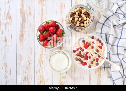 Quick breakfast for kids with corn balls and chocolate corn balls and strawberry on a light kitchen table, top view. Healthy corn balls with milk for Stock Photo