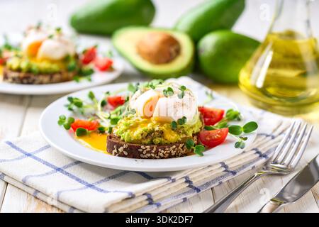 Avocado toast with poached egg over rye bread toast with mashed avocado spread. Healthy breakfast or lunch food. Stock Photo