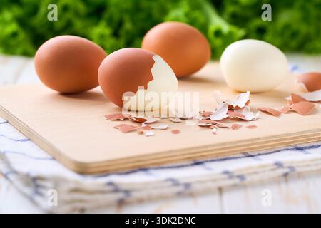 Fresh hard boiled eggs with shell beside in a cutting board, selective focus. Stock Photo