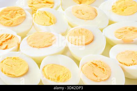 boiled chicken eggs close-up. Background of boiled eggs, top view.  hard-boiled chicken eggs peeled and cut in half as background, top view. Stock Photo