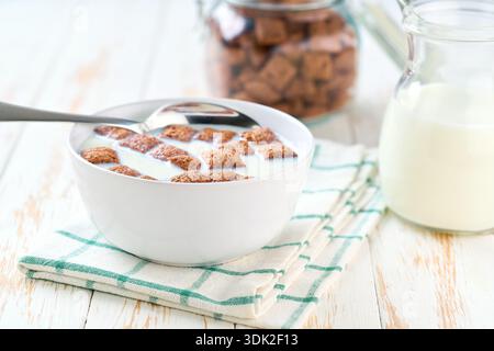 chocolate corn pads in a bowl with milk on a white wooden table.  corn pillows and milk, morning breakfast. Stock Photo