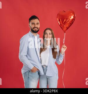 Posing, holding balloon. Lovely couple are together in the studio. Stock Photo