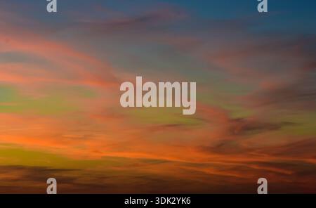 Spectacular evening sky showing a wide range of colors from deep orange to purple and subtle green atmospheric hues. Stock Photo