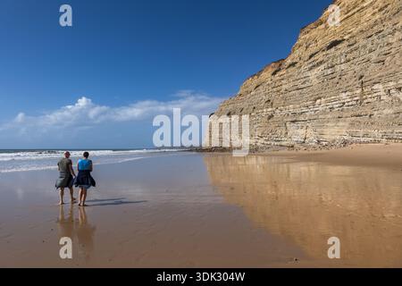 Lonely couple on Praia de Porto Mos sandy beach and cliff in Lagos on Algarve coast, southern Portugal. Stock Photo