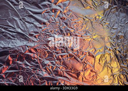 Crumpled aluminum foil texture creating an abstract background with colorful light reflections Stock Photo