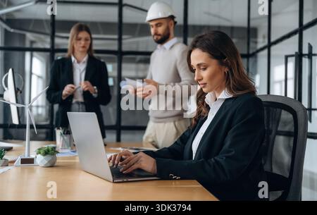 Little model of wind turbine on table. Business people are working in the office. Stock Photo