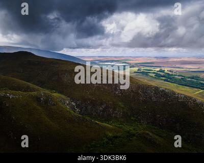 Aerial view of dramatic clouds casting shadows over the rolling hills and distant plains, a symphony of light and shadow, Riviersonderend, Western Cap Stock Photo