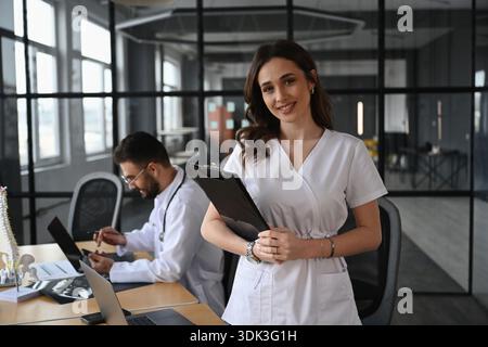 Notepad is in hands. Two doctors are in the office. Stock Photo