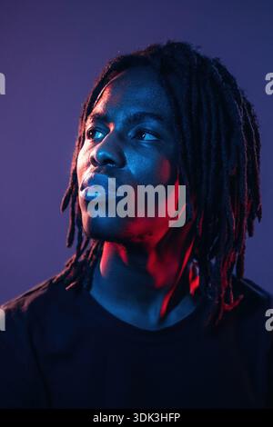 Focused close up view. African American guy is studio with neon lighting. Stock Photo