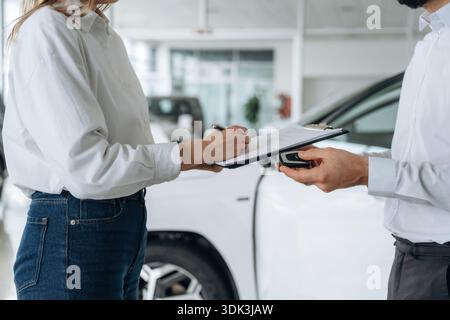 Holding keys for car. Close up view of man and woman is dealership. Stock Photo