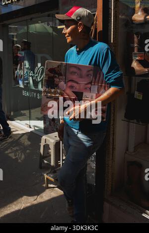Young male standing on sidewalk holding a sign, soliciting business for a beauty salon, Nuevo Progreso, Mexico. Stock Photo