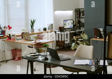 Modern Office Interior Featuring Laptops and Documents on Desks Stock Photo