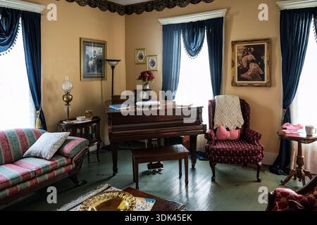Sunlight filters through heavy curtains, illuminating dust motes in the still air of a forgotten parlor. An antique piano sits silent, its dark wood a Stock Photo