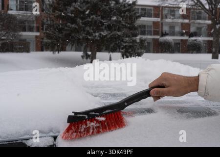 Close-up of a hand using a snow brush to clear snow from the car. A practical tool for keeping your vehicle safe and visible during the winter months Stock Photo