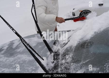 Braving the winter chill to remove snow and ice from the front windshield, making sure the road ahead is clear and safe for driving Stock Photo