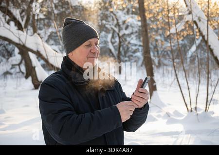 Senior man using smartphone outdoors in winter Stock Photo