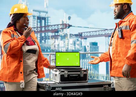 Green screen laptop used by offshore platform workers managing maintenance systems, scheduling infrastructure repairs. Technicians oversee structural integrity of drilling rig with chroma key notebook Stock Photo
