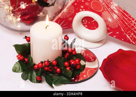 Christmas candle centerpiece with red decorations. Advent holiday table decor. Festive winter still life with warm light and seasonal ornaments. Stock Photo