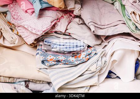 Pile of folded clothes stacked after laundry at home. Clean textiles prepared for storage and organization. Household clothing management. Stock Photo