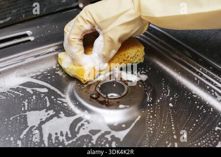 Cleaning gas stove with sponge and detergent foam during household chores. Manual removal of grease and food residue from gas burners. Kitchen hygiene Stock Photo