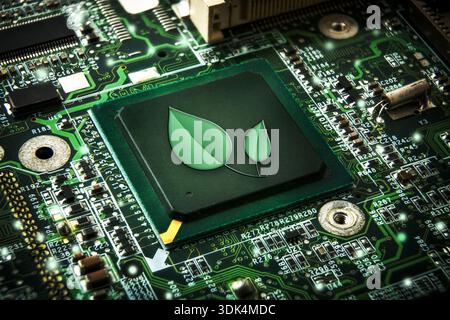 Low-power processor concept with green leaf symbol mounted on a green motherboard with electronic components. Elevated view. Stock Photo