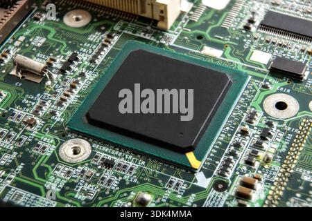 A detailed close-up of a processor mounted on a printed circuit board, surrounded by soldered electronic components and fine circuit traces, represent Stock Photo