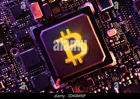 Glowing Bitcoin symbol embedded in a microchip on a circuit board, representing cryptocurrency, blockchain technology, and the fusion of digital finan Stock Photo